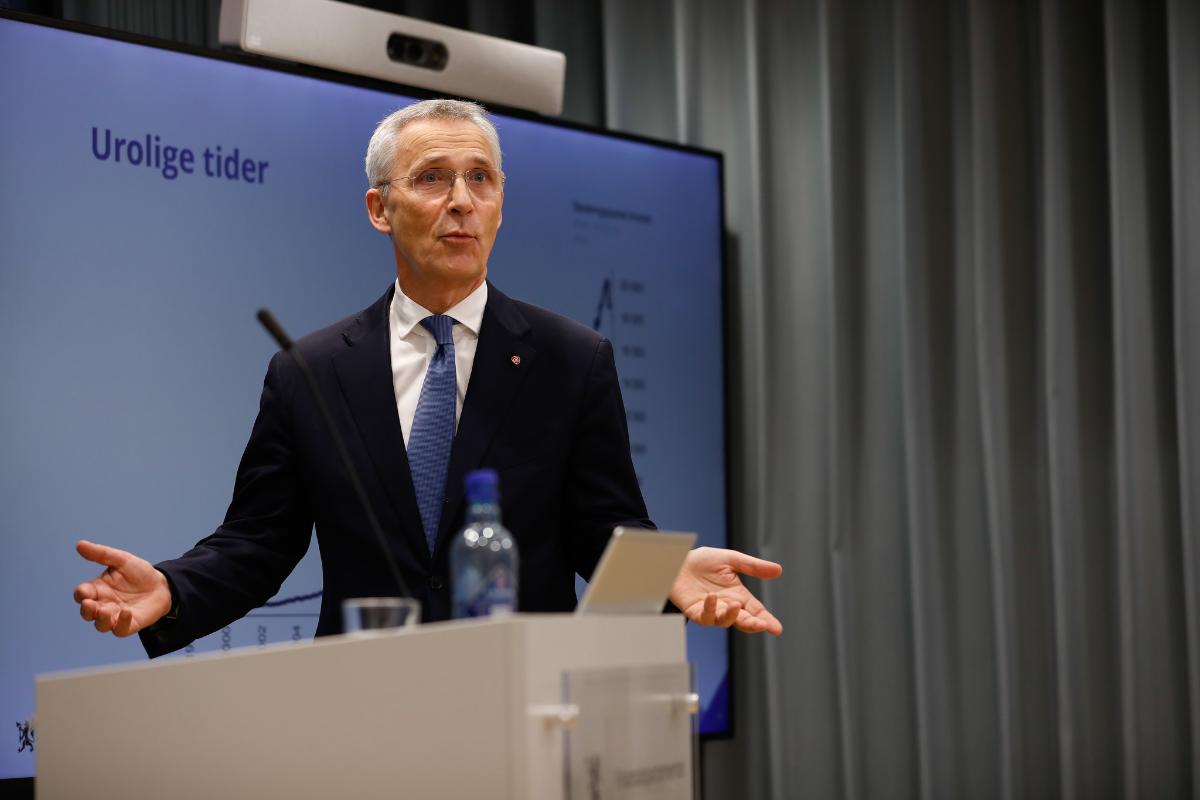 Mann på podium snakker til publikum i salen